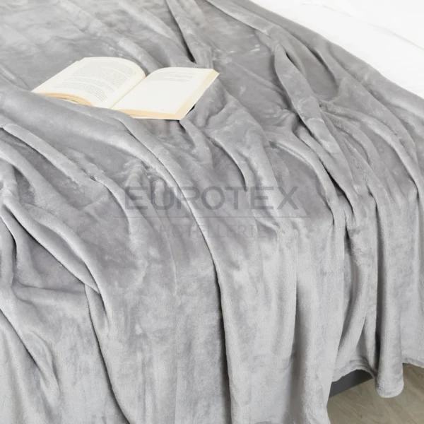 Coperta Plaid Dehor colore tortora distesa sul letto con libro aperto