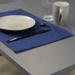 Tovaglietta idrorepellente no stiro Elite in tessuto jacquard blu con piatti e posate