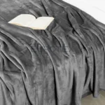 Coperta Plaid Dehor colore antracite distesa sul letto con libro aperto