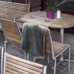 Coperta Plaid Dehor colore antracite piegata e appoggiata su una sedia in un tavolo all'esterno