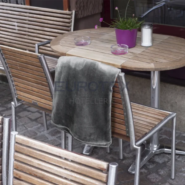 Coperta Plaid Dehor colore antracite piegata e appoggiata su una sedia in un tavolo all'esterno